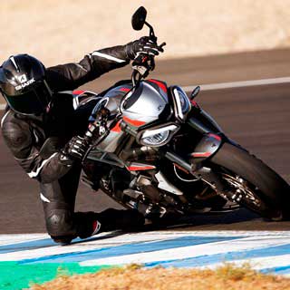 Rider on new Triumph Street Triple RS in Silver Ice with his knee down corning on the racetrack
