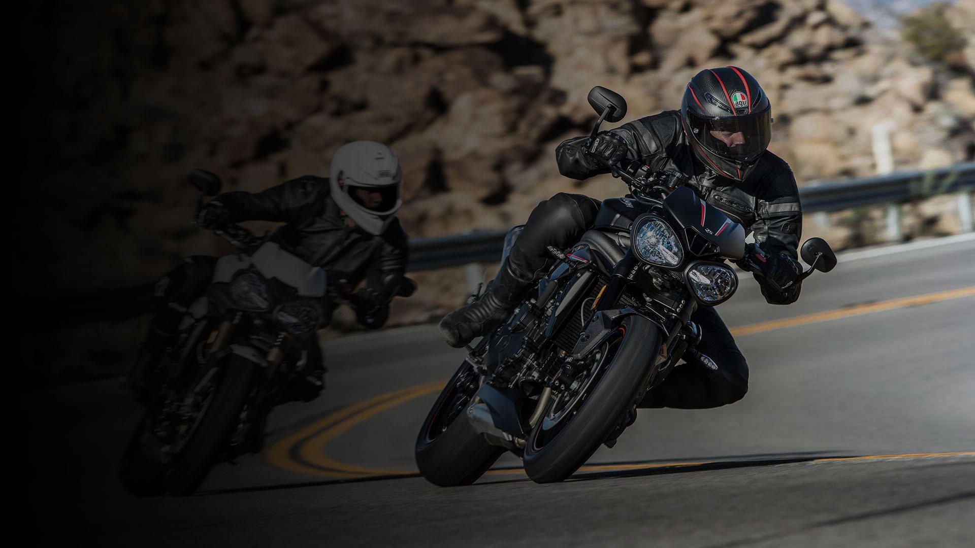 Triumph Speed Triple cornering on a tight bend with a black fade on the left hand side, covering another rider