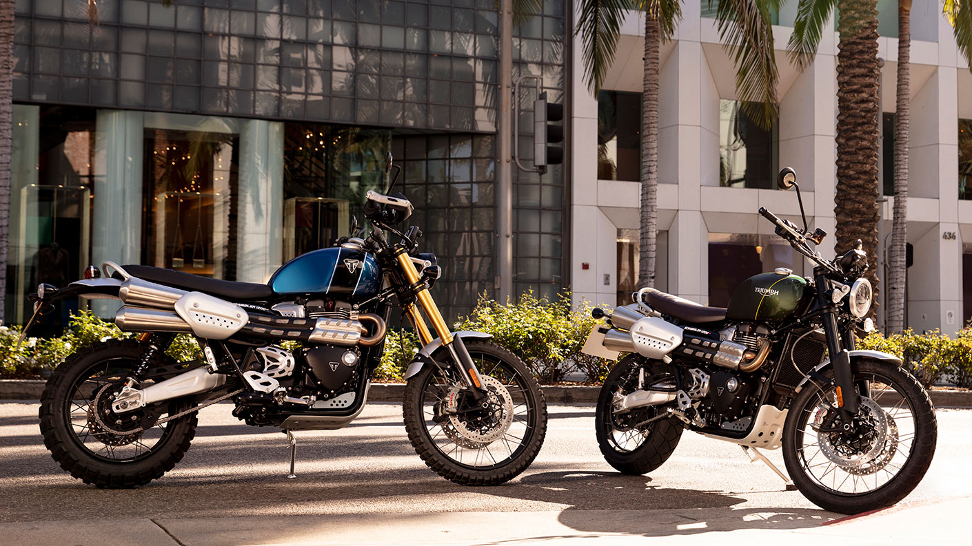 Two Triumph Scrambler 1200s parked in urban area, with sunlight highlighting iconic modern classic styling