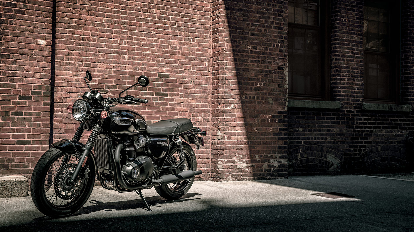Triumph Bonneville T100 motorcycle parked near a brick wall