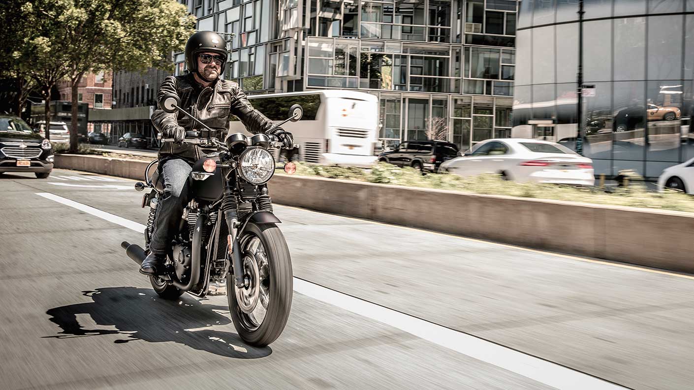 Triumph bonneville T120 black riding through city